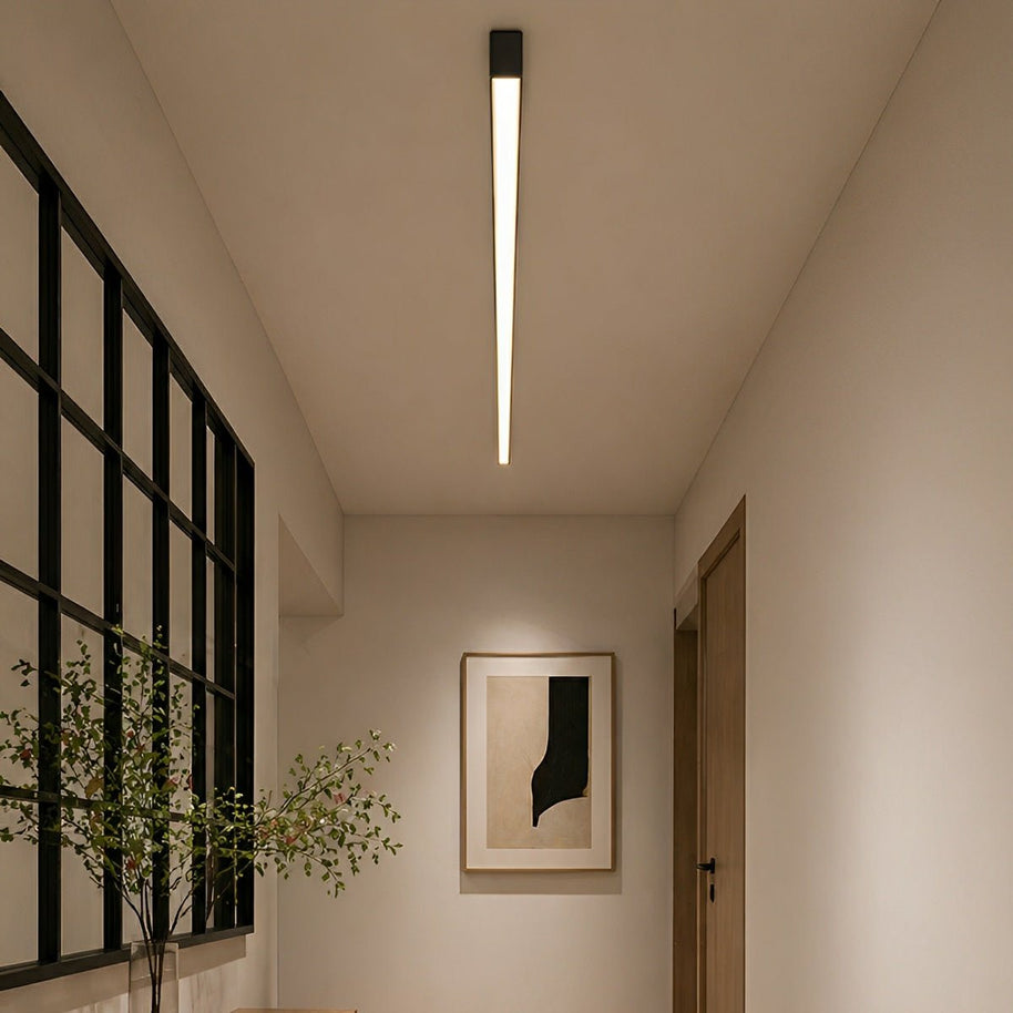 Slim linear ceiling light fitted along a hallway ceiling beside black-framed glazing.