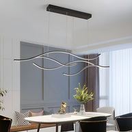 Linear pendant light made of wavy LED bars hung from a slim rectangular canopy, lit, above a round dining table in a panelled room.