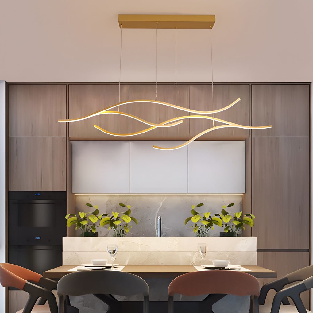 Linear pendant light made of wavy LED bars hung from a slim rectangular canopy, lit, above a dining table in a wood-panelled kitchen.
