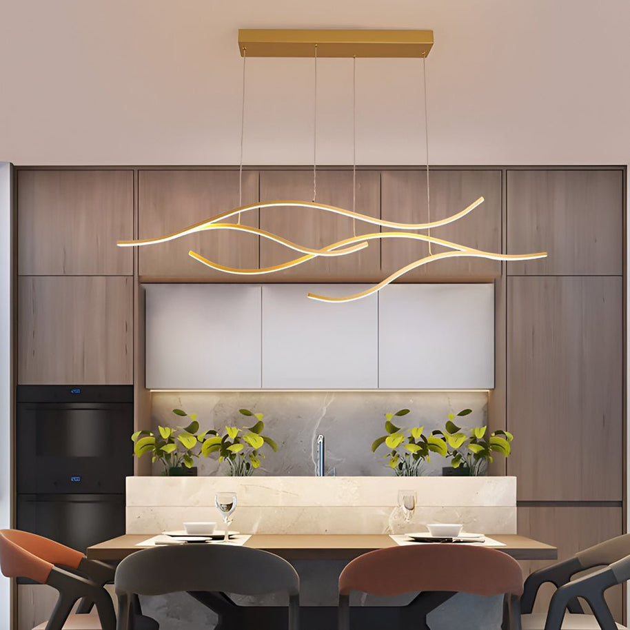Linear pendant light made of wavy LED bars hung from a slim rectangular canopy, lit, above a dining table in a wood-panelled kitchen.