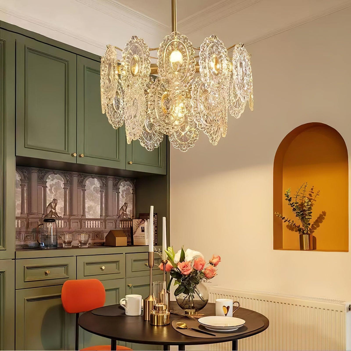 Ondessa Wave Glass Chandelier, gold/clear lit over bistro table, green cabinetry