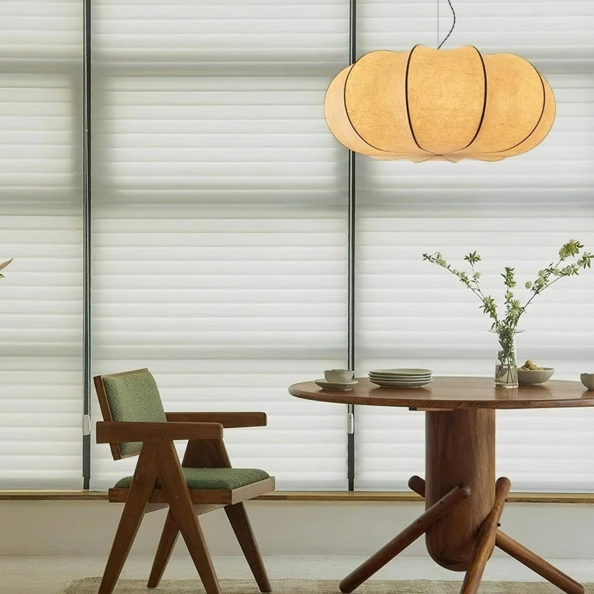 Silvara Pendant Light with a ribbed fabric shade, lit, above a round wooden dining table