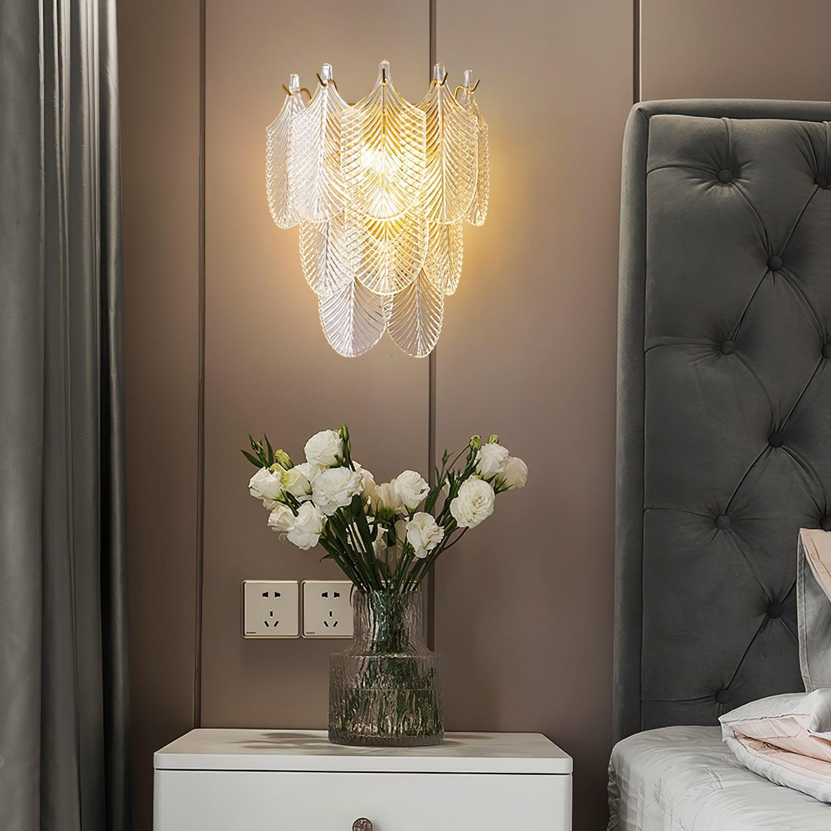 Tiavera Tiered Glass Wall Sconce, lit above white nightstand with flowers, bedroom