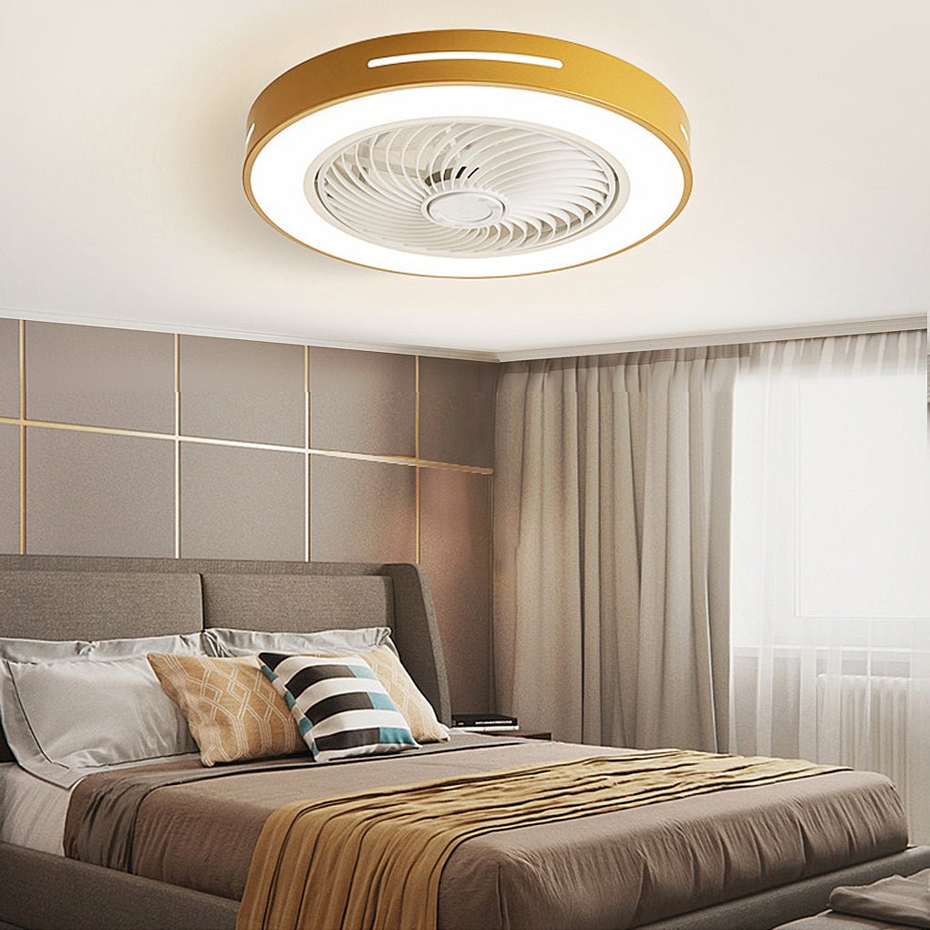 Flush-mount ceiling fan with an enclosed blade cage and a lit ring, gold-toned outer rim, fitted to a bedroom ceiling above a bed.