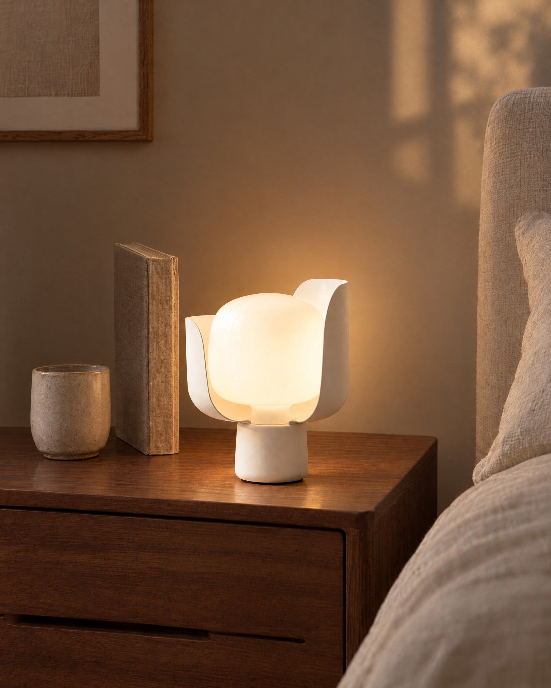 Pethella Table Lamp in White on a walnut bedside table beside a book and a cup